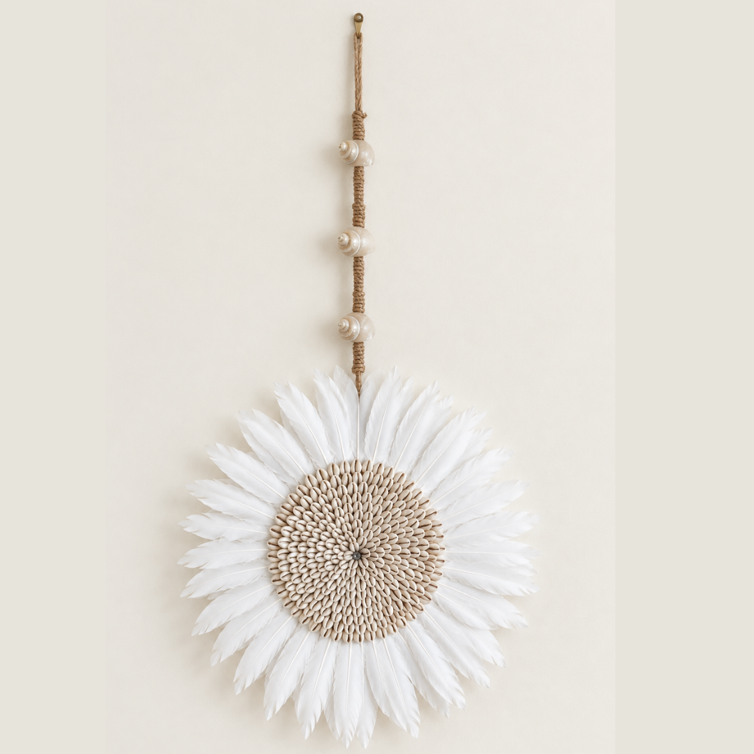 Small white feather wall hanging with a cowrie shell centre, suspended from a knotted jute cord with three spiral shells.