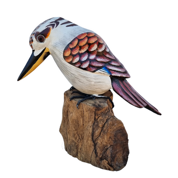 A hand-carved wooden Kookaburra bird with detailed paintwork perched on a wooden stump.