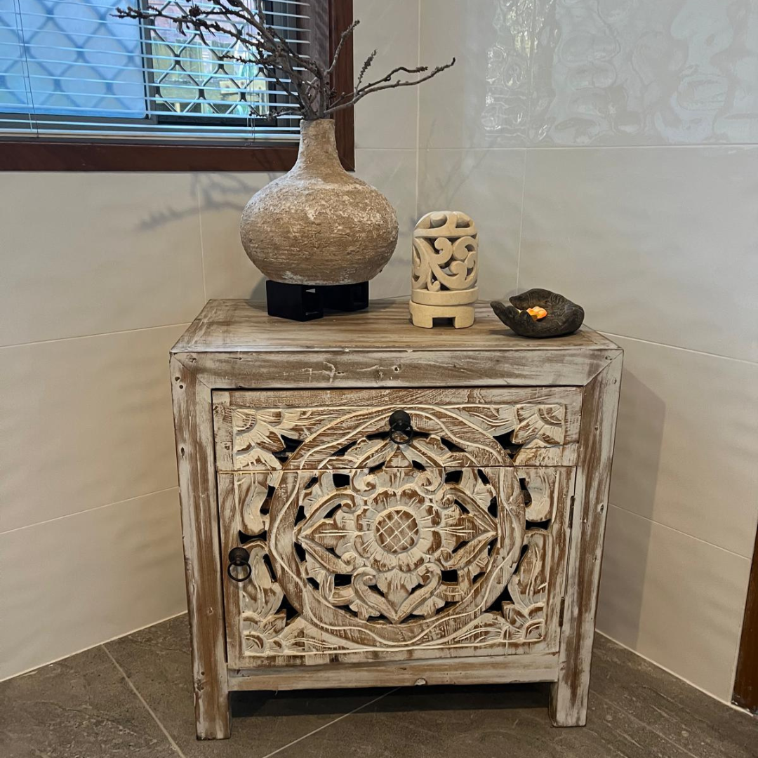 Reclaimed teak Mandala bedside table styled with a textured stone vase, carved candle holder, and decorative bowl in a warm neutral interior setting