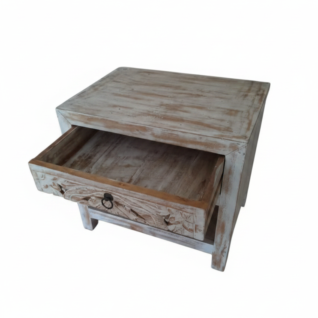 Top-down angled view of whitewash teak bedside table with drawer pulled open showing natural raw timber interior and carved floral drawer front