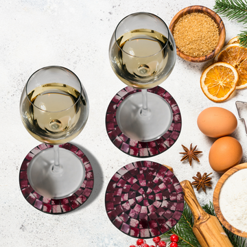 A set of round mosaic drink coasters in various colors, displayed alongside glasses of white wine and an assortment of food items.