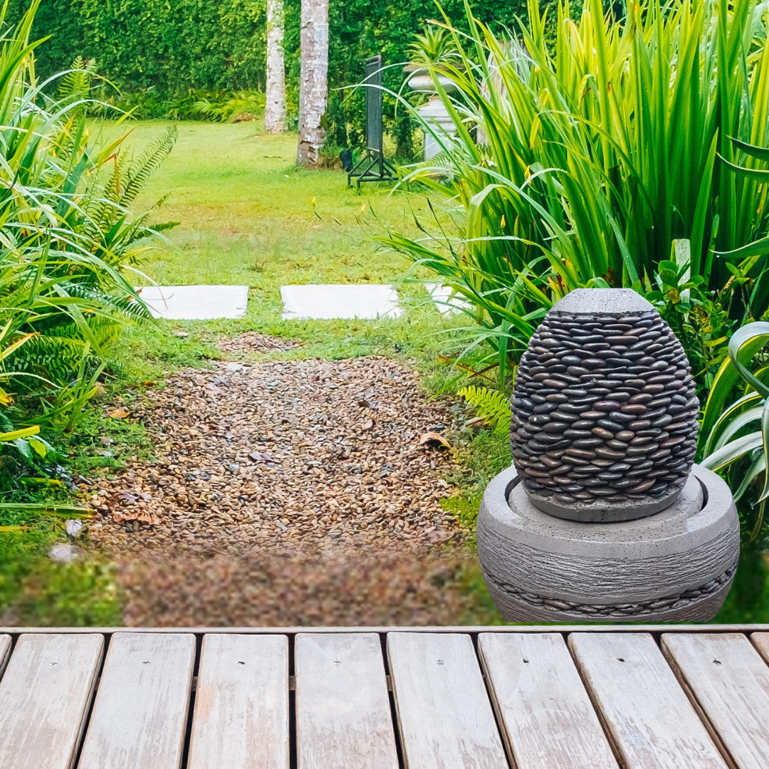 Decorative stone sculpture on a wooden deck with a garden path and greenery in the background
