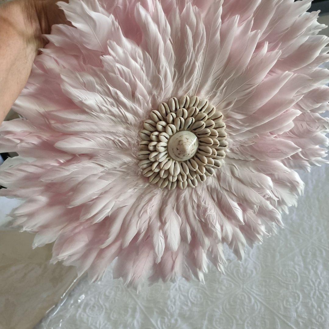 Close-up of a pink feathered decorative item on a textured white surface