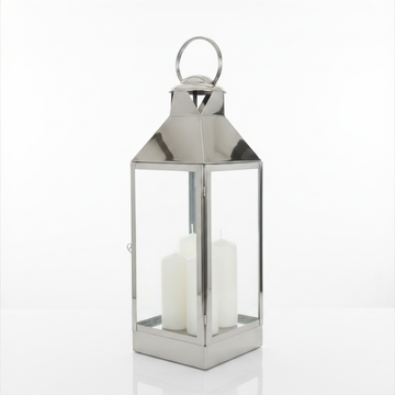 Large polished silver metal lantern with solid pyramid roof, round loop handle, and two white pillar candles, photographed on a white background