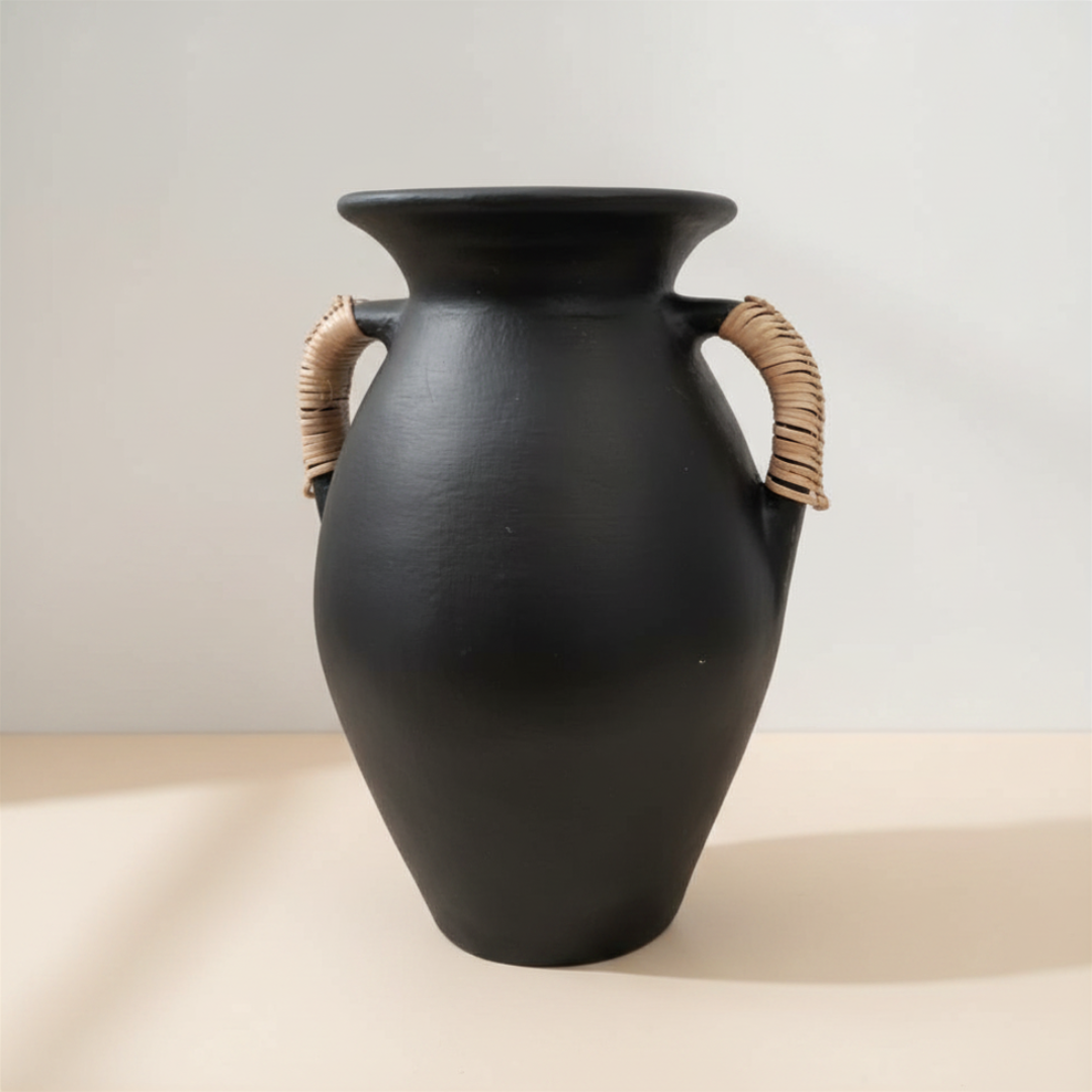 Matte black terracotta vase close up showing rattan handle detail and smooth matte finish, warm shadow on neutral background