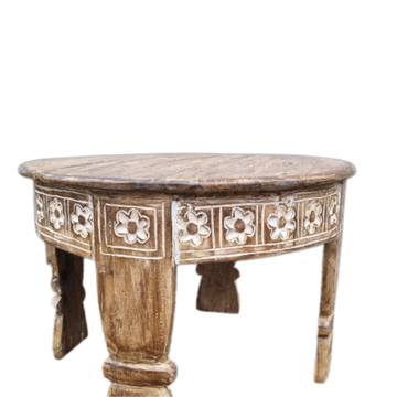 Close-up of hand-carved floral panel detail on a reclaimed teak wood round coffee table — natural distressed wood grain on white background