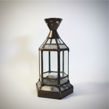 Style 2 rustic metal lantern with hexagonal clear glass panels, etched decorative glass border strips, ornate cone top, and small tealight candle inside, in dark bronze finish on a grey background