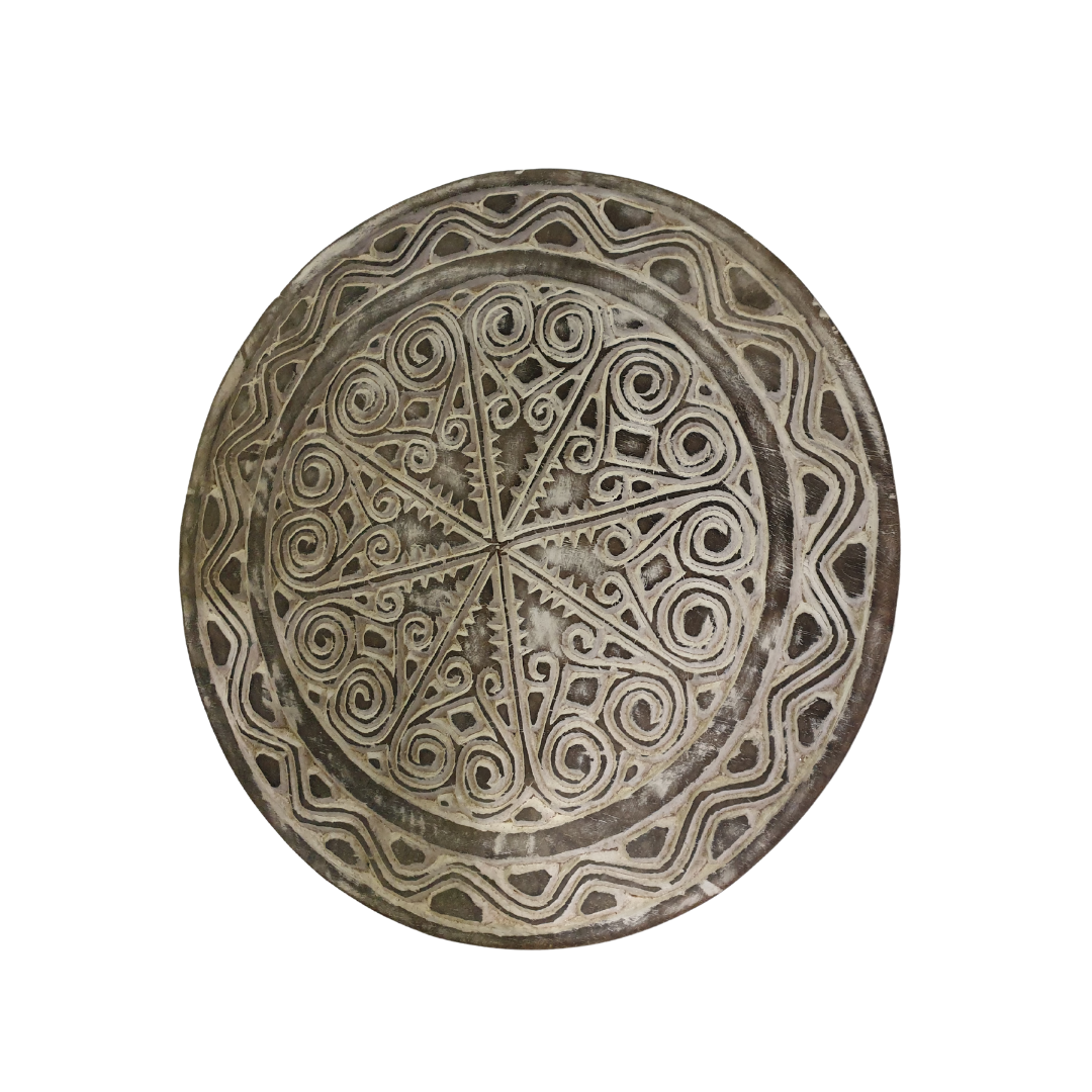 Angle shot of a rustic wooden circular wall hanging with whitewash finish on a white wall, tribal-inspired décor