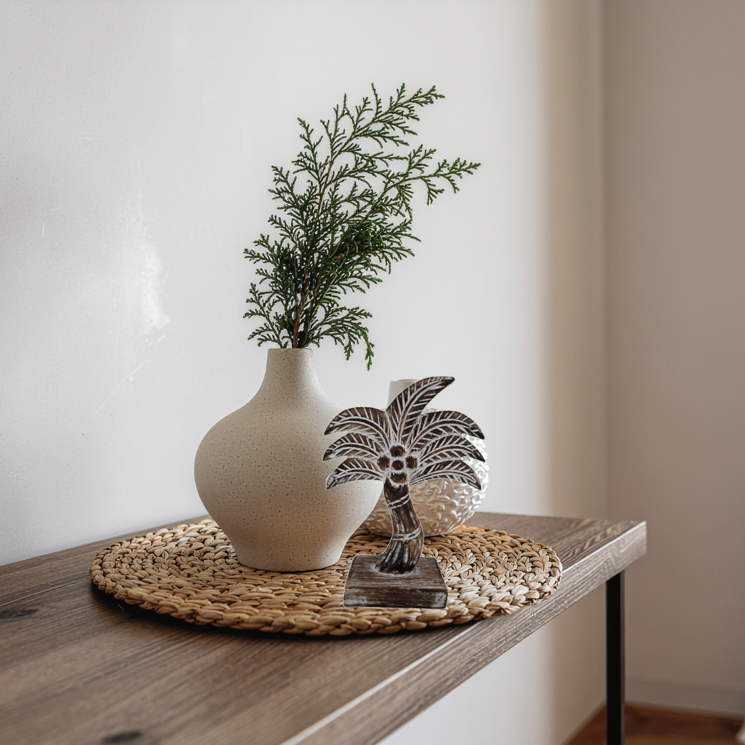 Decorative items including a vase with greenery, a palm tree sculpture, and a white vase on a wooden surface.