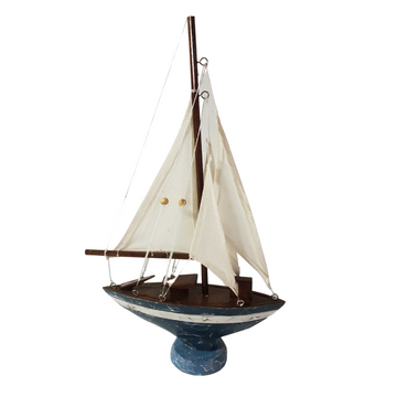Wooden sailboat with cream fabric sails, a distressed blue hull and white stripe on a blue pedestal against a white background