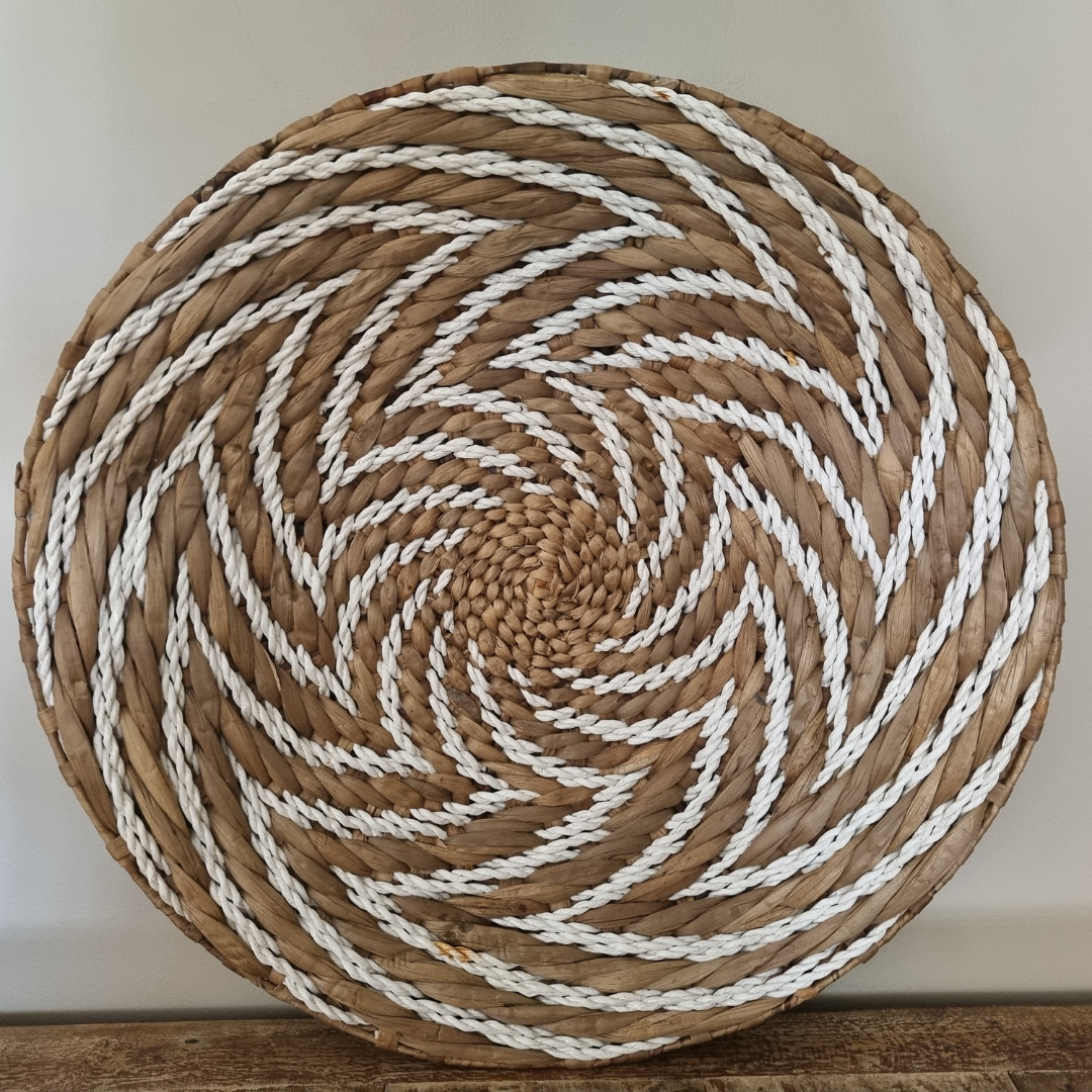 Large handwoven seagrass spiral wall art leaning on timber surface – brown natural fibre with white rope spiral detail, ready to hang Australia