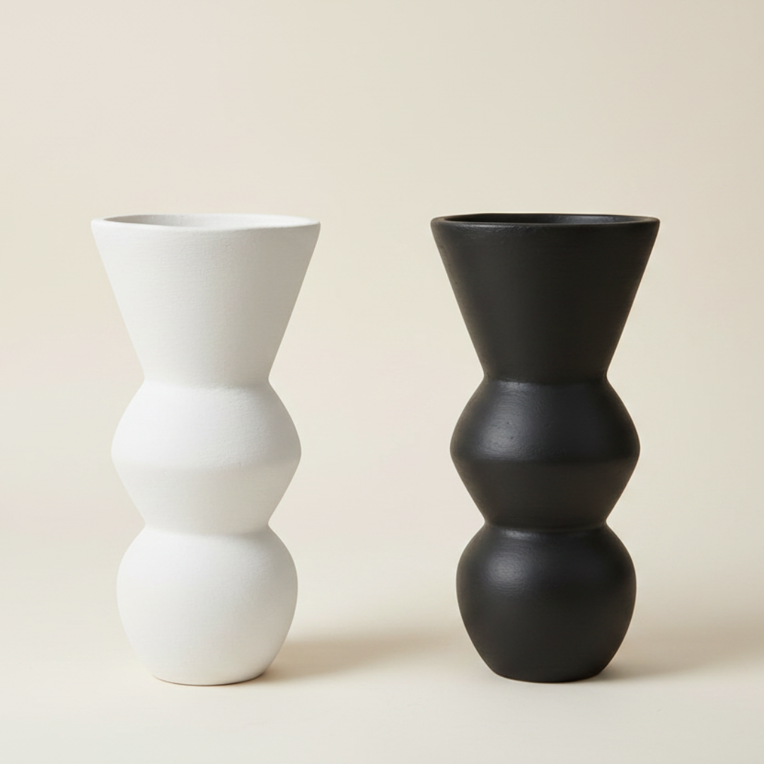 Two sculptural decorative objects side by side on a white background — one matte white, one matte black, showing both colour options