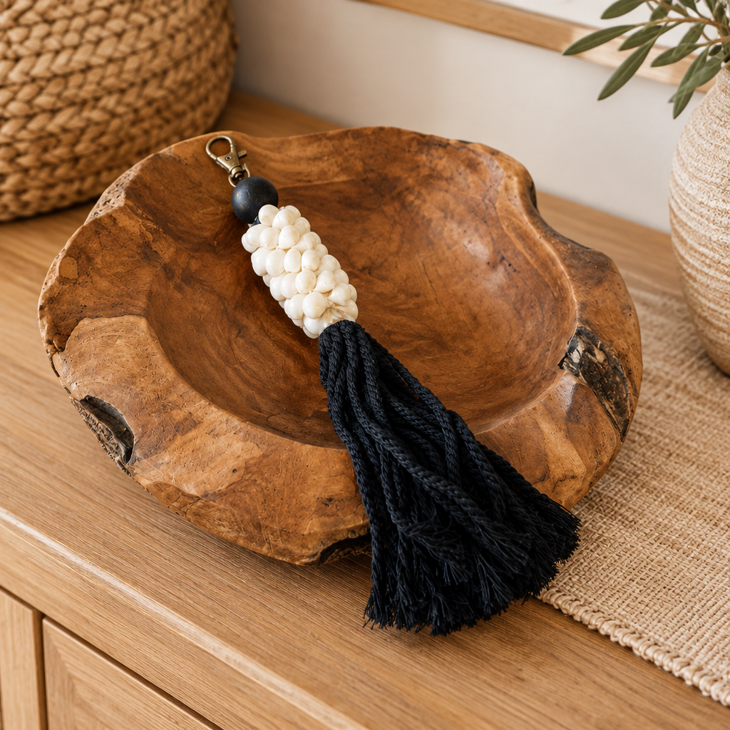 Black in wooden bowl: Black cotton strands and a pale bead cluster spilling over a rustic carved wooden bowl.