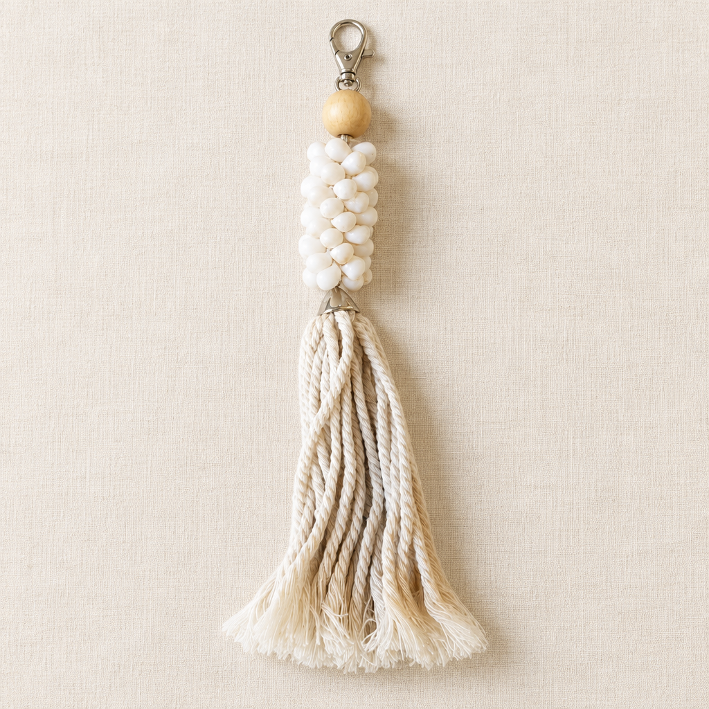 Natural on linen: Cream braided cords with pale beads and a silver-tone clip on an ivory linen surface.