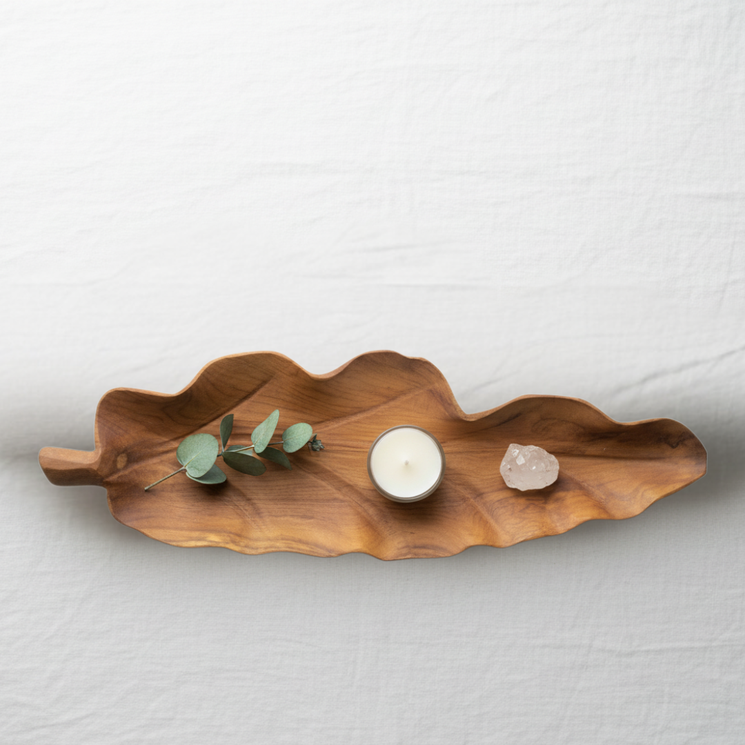 Top-down flat lay of handcrafted teakwood leaf tray Style 1 styled with eucalyptus, tea light candle and crystal on white linen — coastal home decor
