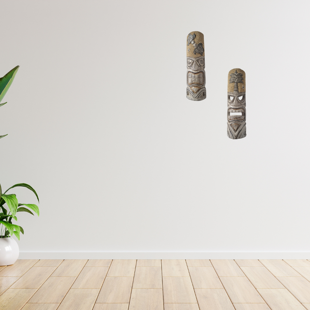 Two tribal masks on a white wall with a wooden floor and plant.