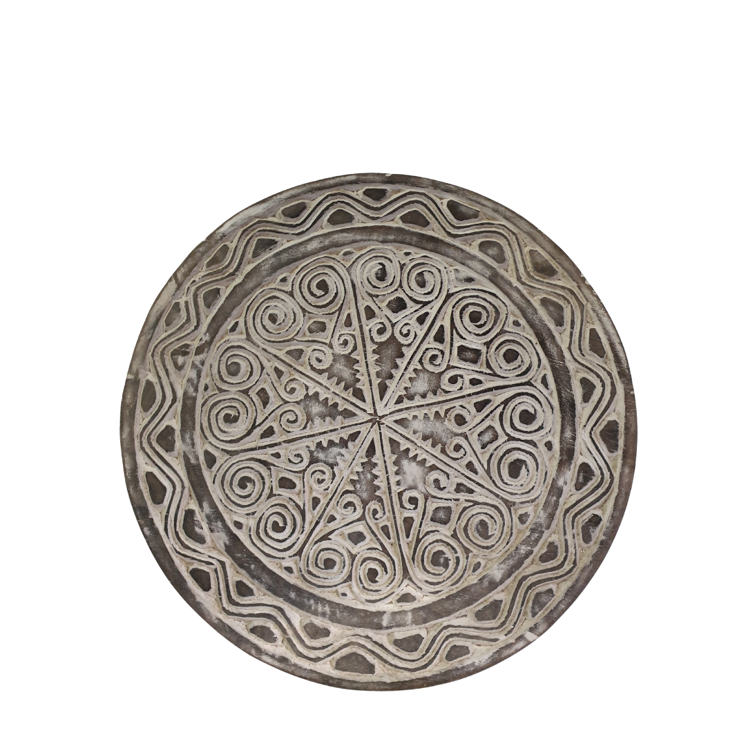 A photo shot of a rustic wooden circular wall hanging with whitewash finish on a white wall, tribal-inspired décor