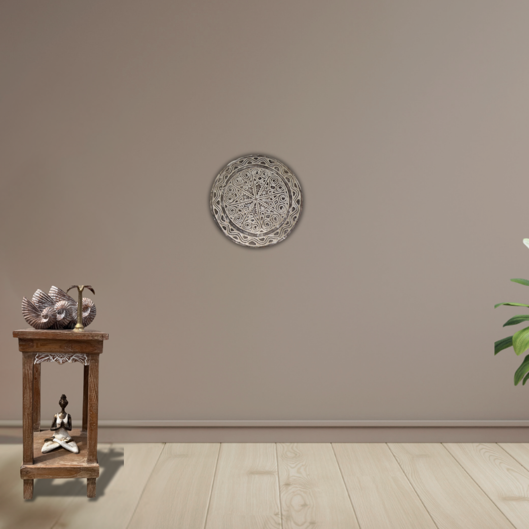 Decorative wall plate on a beige wall with a wooden side table and plant in the corner.