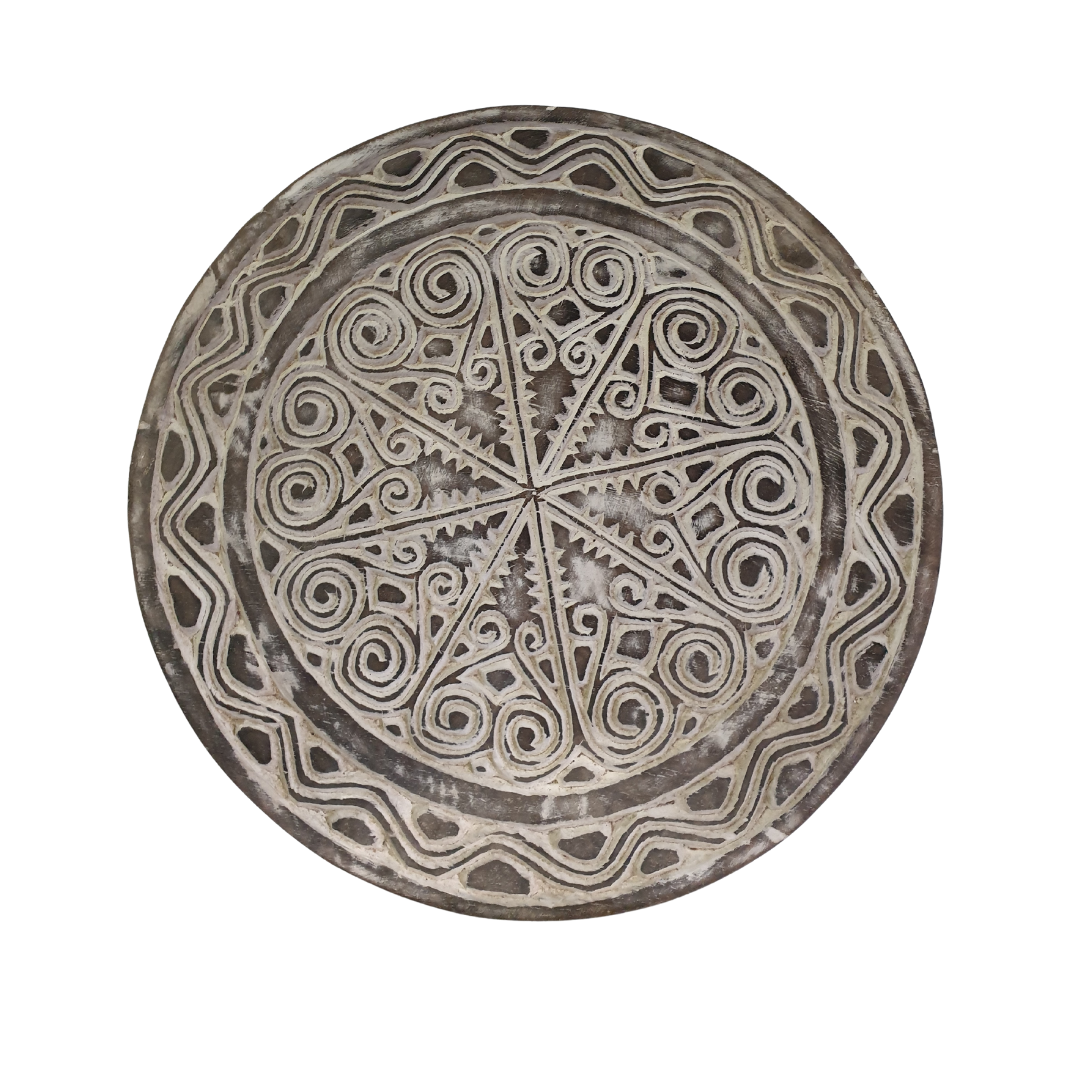 A photo shot of a rustic wooden circular wall hanging with whitewash finish on a white wall, tribal-inspired décor