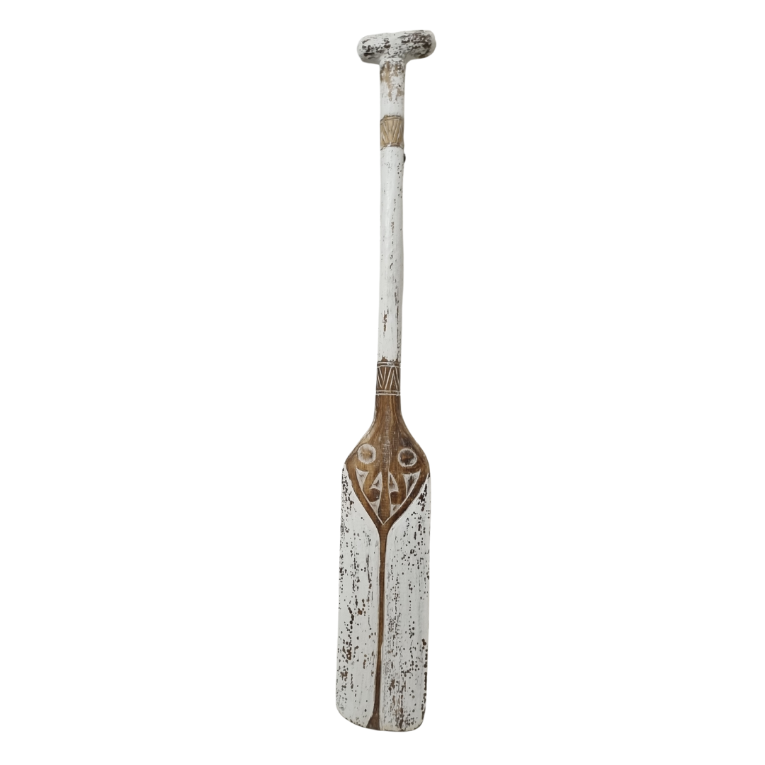 wooden paddle caved in a rustic white wash finish on a white back wall