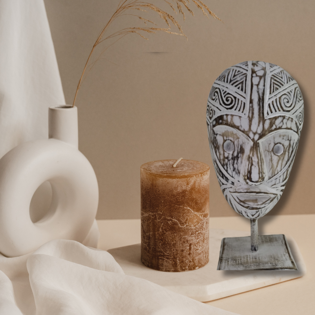 White-wash tribal wooden mask on stand styled with pillar candle and ceramic vase in earthy boho setting | Azure Decor