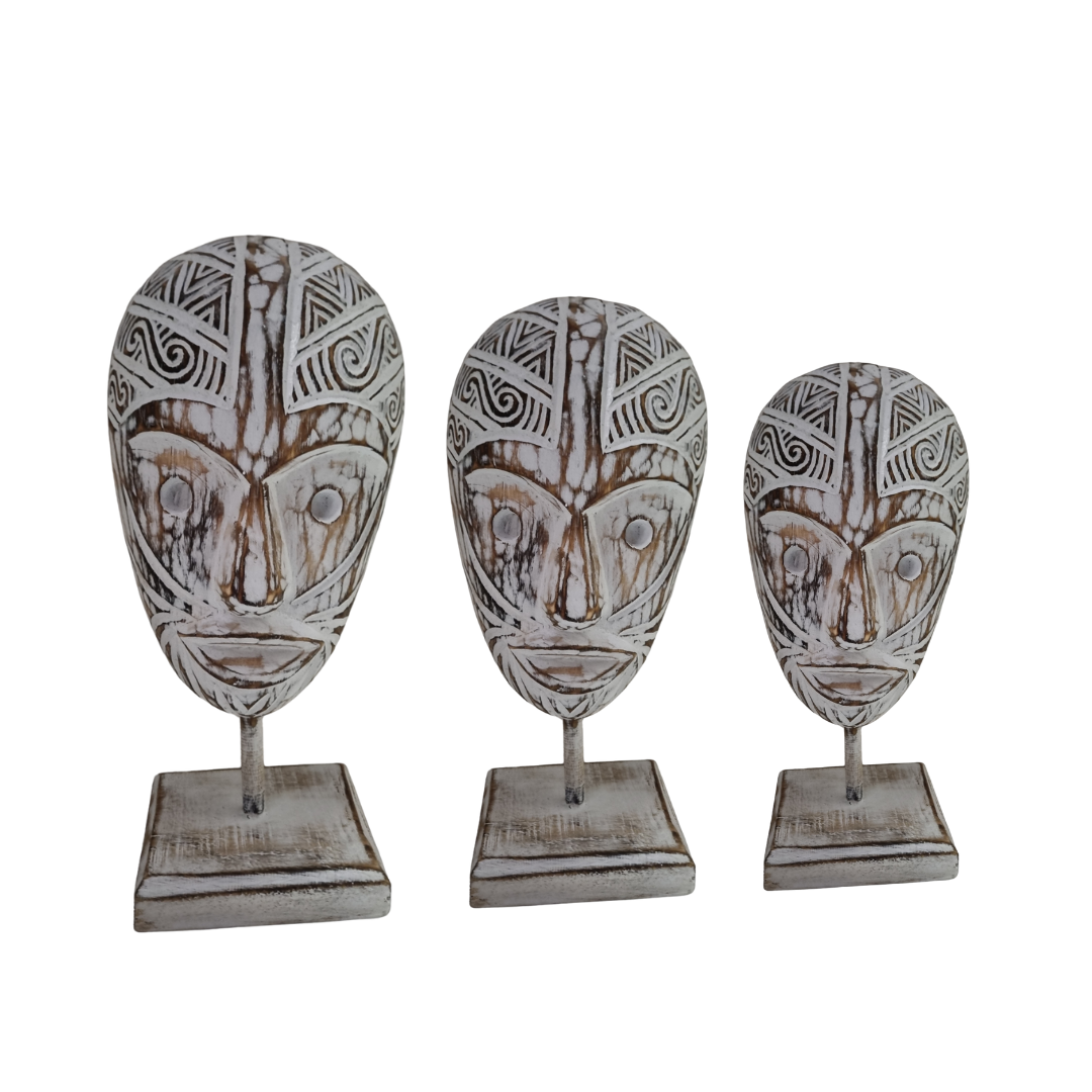 A set of three wooden head sculptures with intricate patterns, mounted on stands and finished in a rustic whitewash, displaying varying sizes.