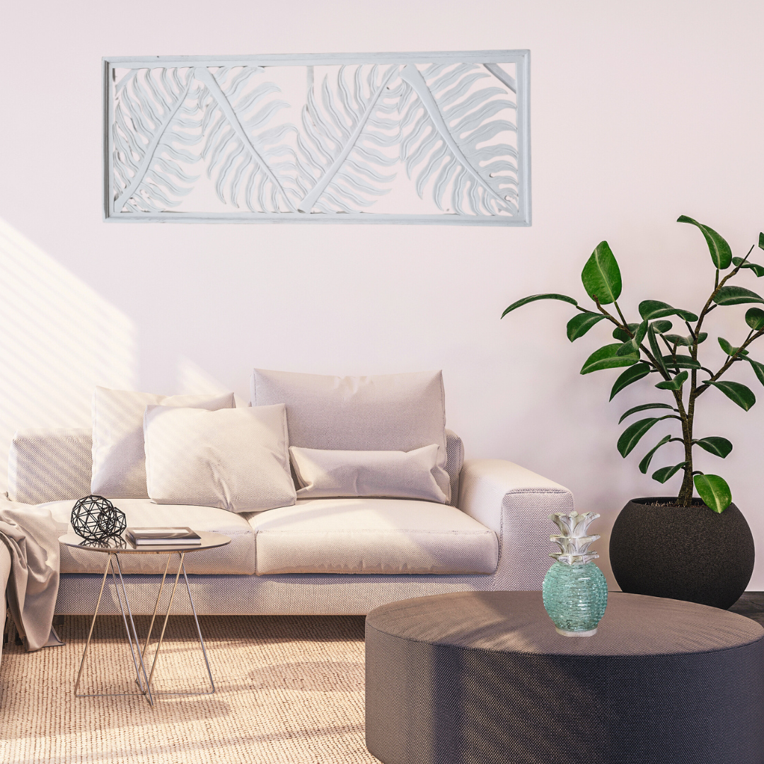 Tropical fern leaf wall hanging in white wash finish displayed horizontally above a sofa in a modern coastal living room