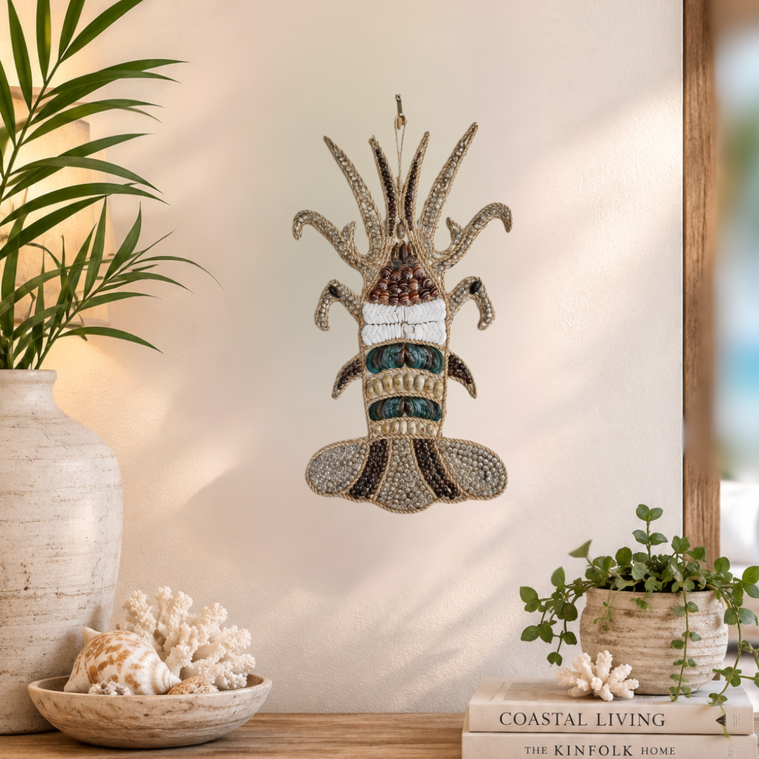 Sculpture styled on a warm peach wall beside a textured white vase, coral pieces and a bowl of shells on a timber console