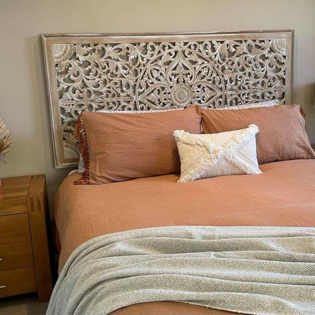 Bed with decorative headboard, pillows, and blanket in a bedroom setting.