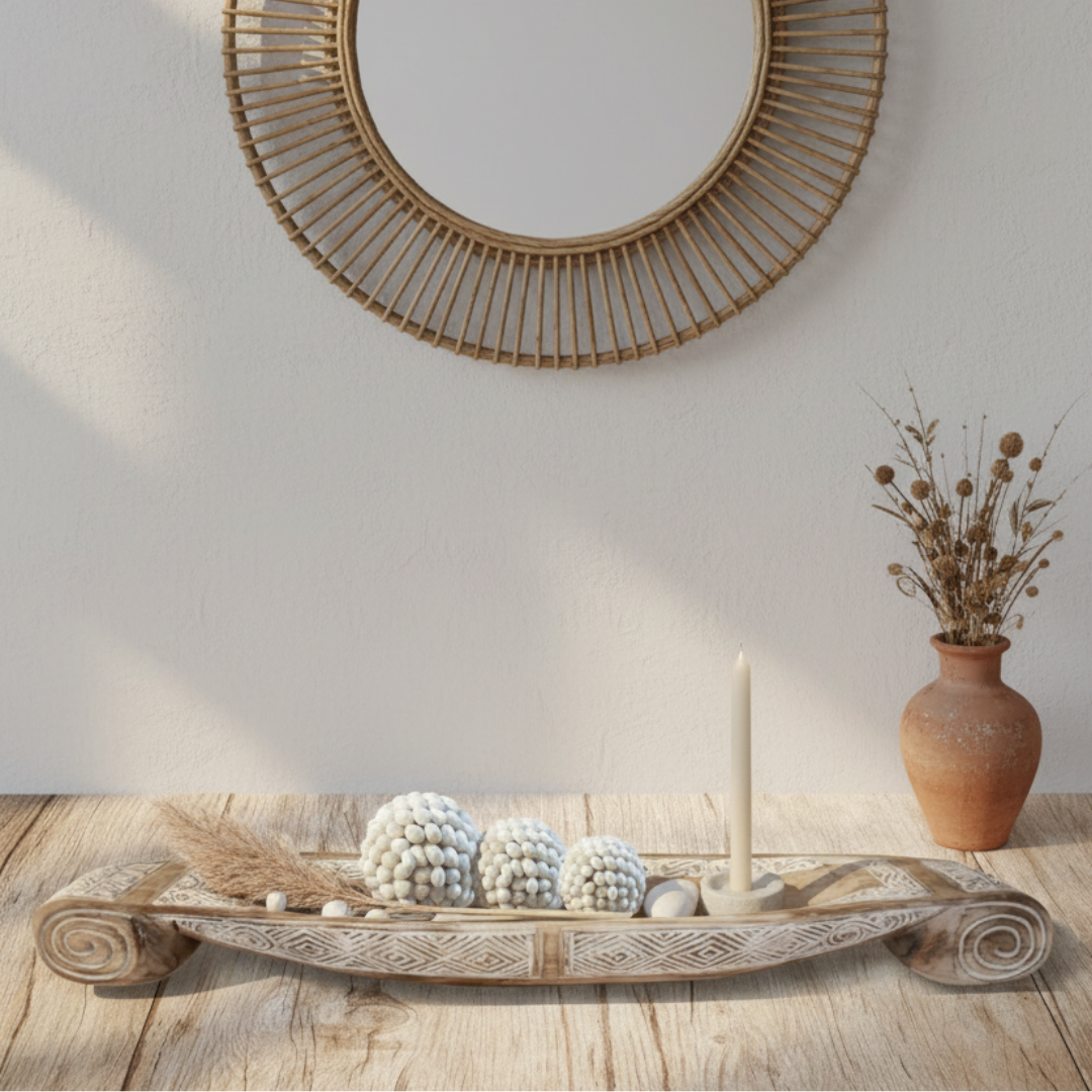 Decorative tray with spherical objects, a candle, and a vase on a wooden surface with a wall mirror in the background.