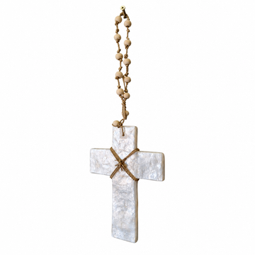 Angled view of a pearly white cross showing its slim edge, tied brown cord and wooden beaded hanger