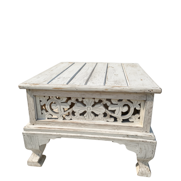 Square low-profile wooden coffee table with distressed white finish and intricate floral carvings on the front panel, isolated on white background
