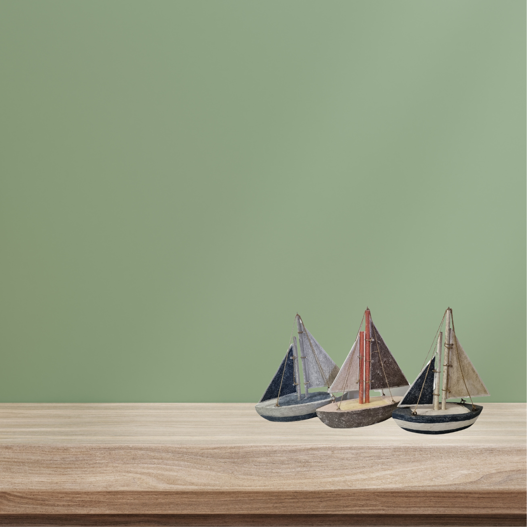 Three model sailboats on a wooden surface with a green background
