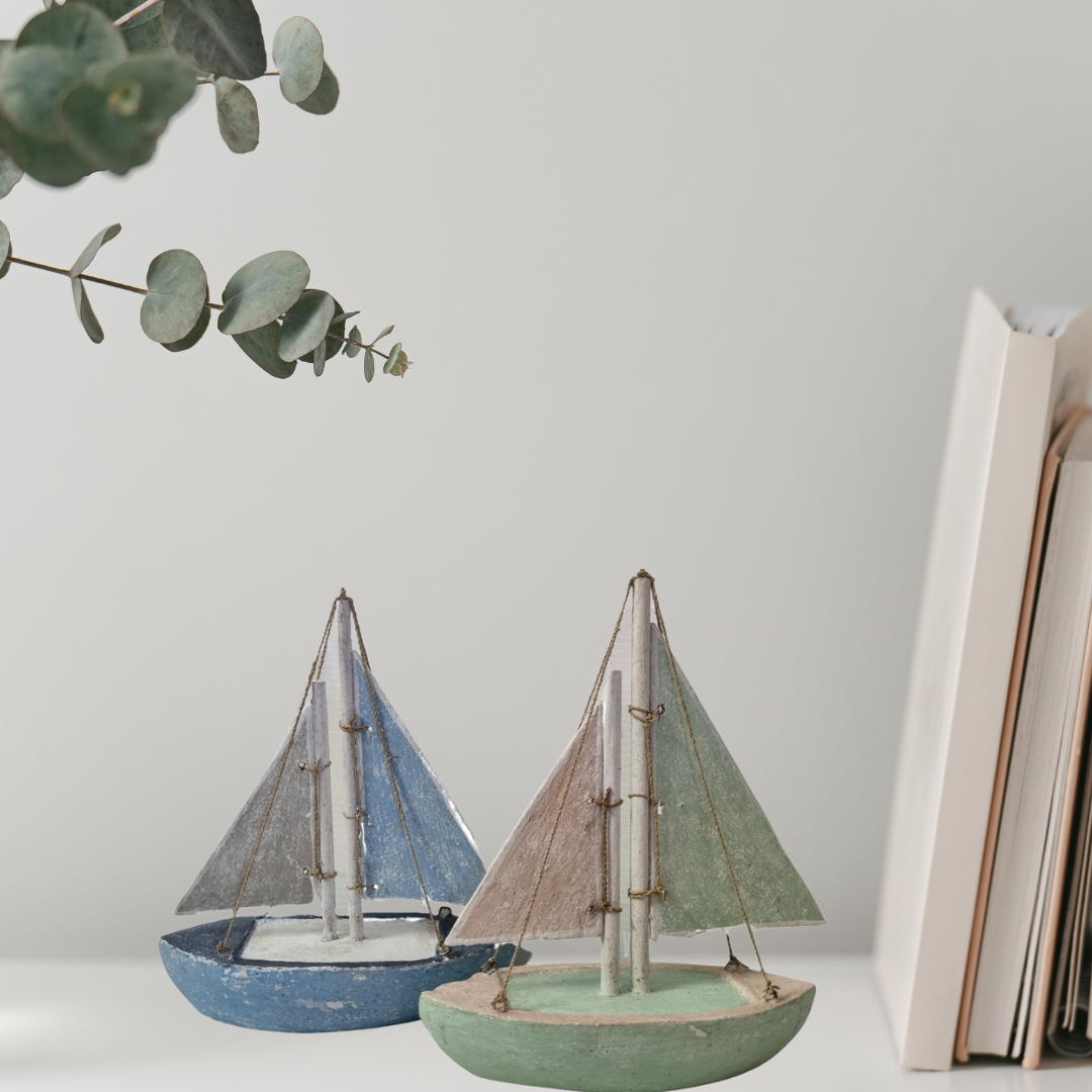 Two small sailboat models on a surface with a light gray background
