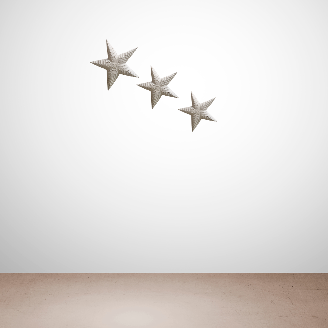 Three decorative stars on a white wall with a wooden floor.