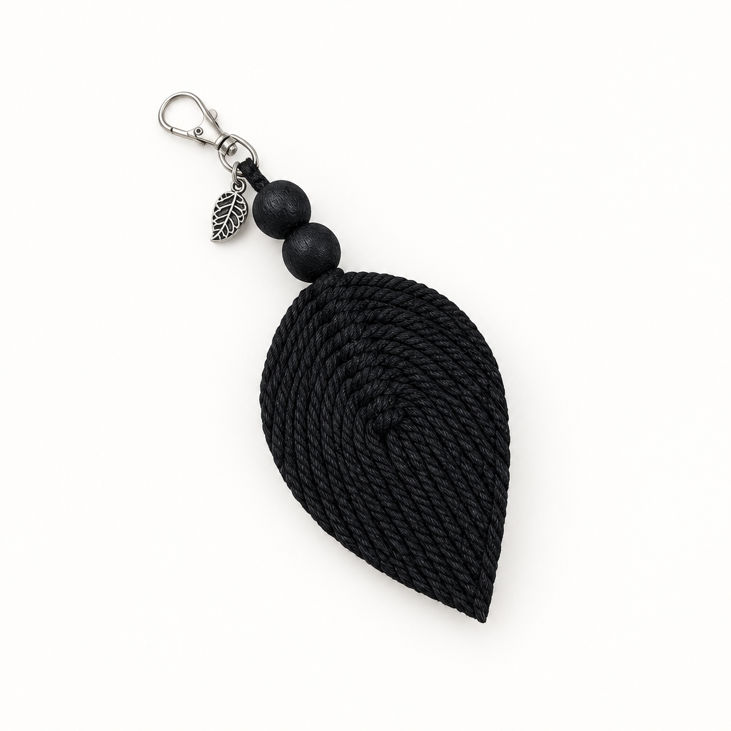 A black teardrop-shaped woven rope tassel keychain with two matte black beads, a small silver leaf charm, and a silver lobster clasp, shown on a plain white background.