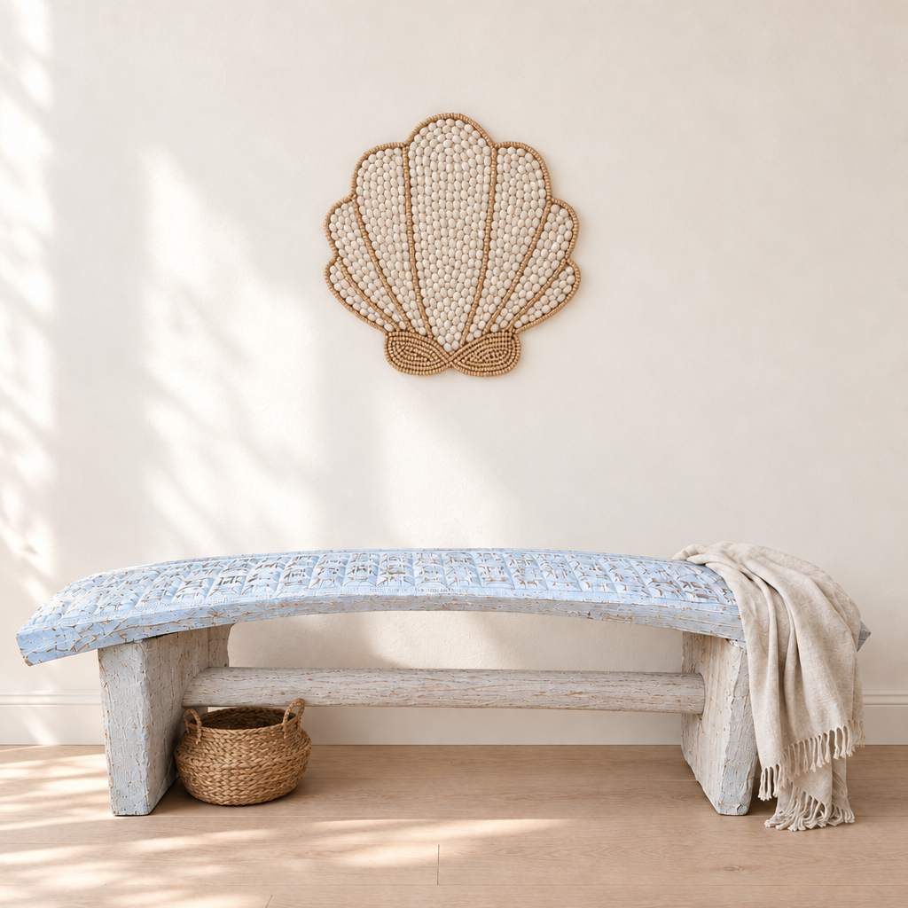 Ivory and beige fan-shaped decoration above a whitewashed carved timber bench, with a woven basket underneath and a fringed linen throw.
