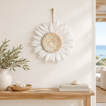 White feathered circular wall decoration displayed above a narrow timber console in a bright coastal interior