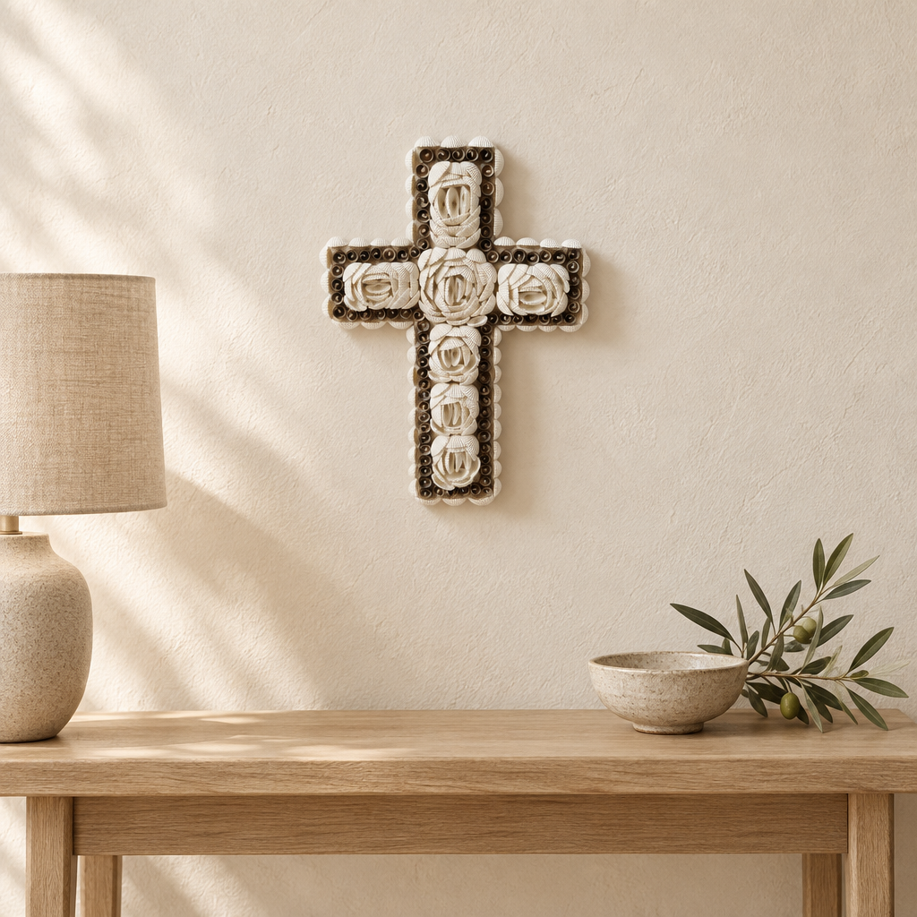 Shell cross wall art above a timber console with a neutral lamp, ceramic bowl and olive branch