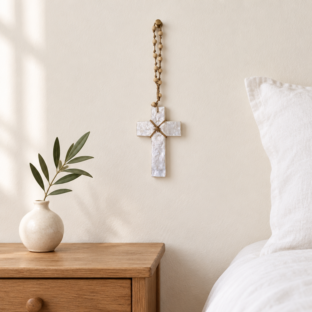 Small pearly white cross hanging from a wooden beaded cord beside a timber bedside table