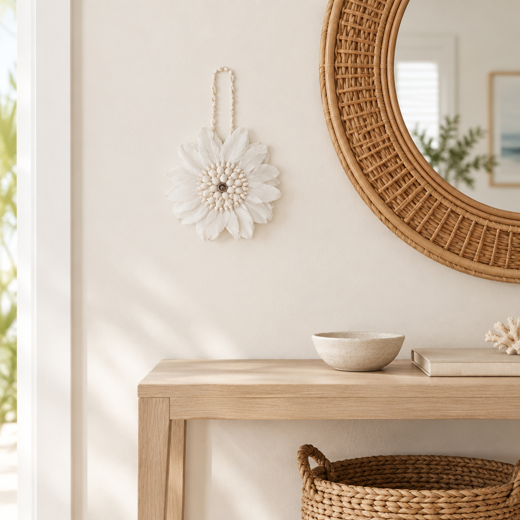 White feather and shell hanging displayed beside a round rattan mirror above a pale timber entryway console.