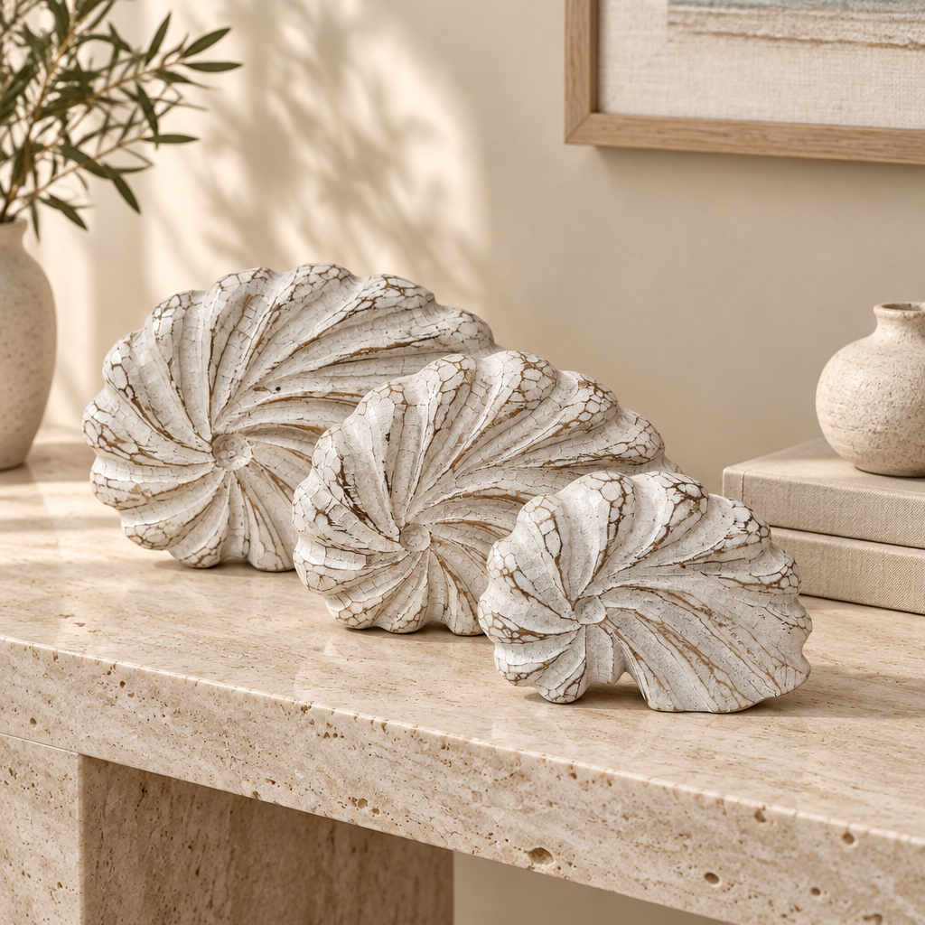 Three graduated white-wash carvings styled on a travertine console