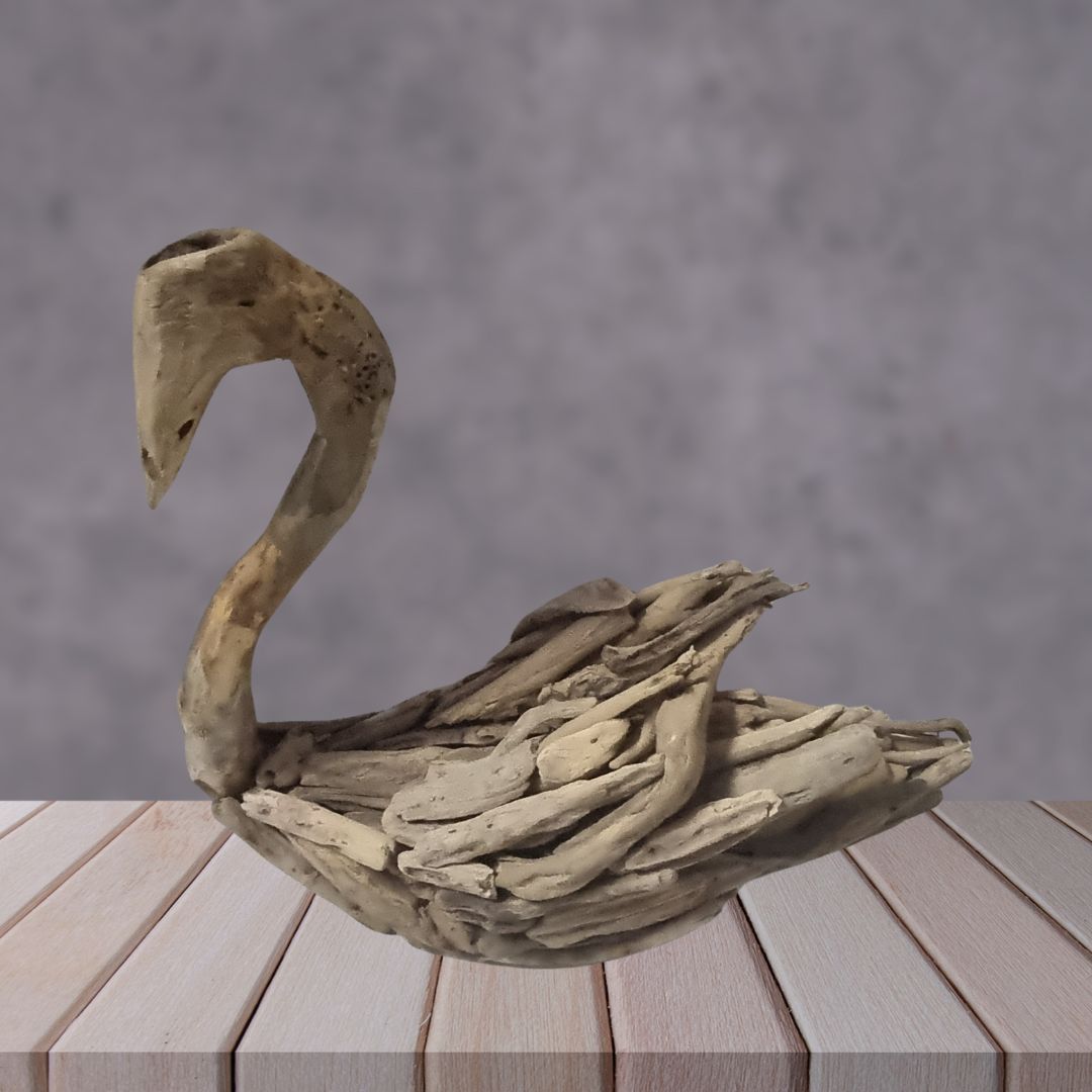 Driftwood sculpture of a swan on a wooden surface with a gray background