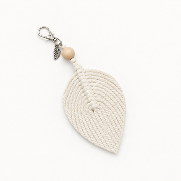 An off-white woven rope leaf keychain charm with a silver metal lobster clasp, a small silver leaf charm, a light wood bead, and a silver metal sprig accent, shown on a plain white background.